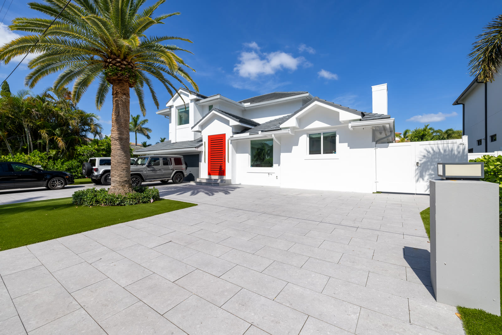 Front exterior of a modern home on Harbor Isle Dr. in Boca Raton with a red front door and circular driveway