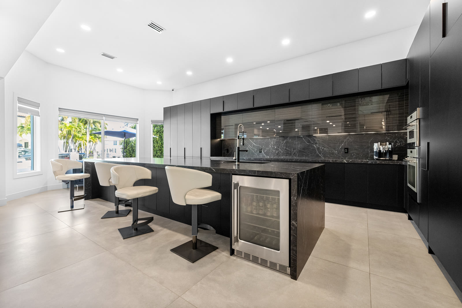 Sleek black marble kitchen island and bar seating in a Boca Raton home