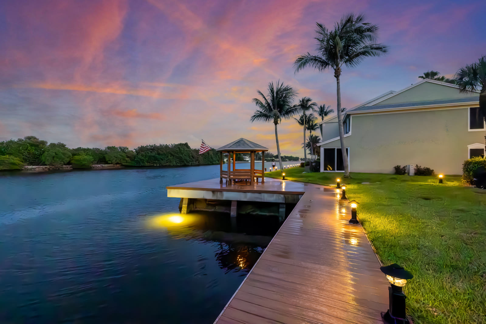 Twilight photograph of a screened pool and lanai overlooking the backyard
